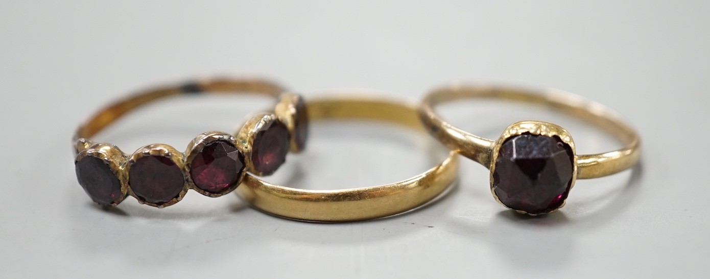 Two 19th century yellow metal and garnet set rings, including five stone half hoop, size J and single stone, size G/H and a yellow metal posy ring inscribed 'Vertue Gaineth Glory', gross weight 2.9 grams.